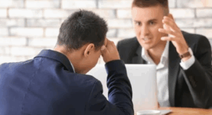 Échange entre manager et collaborateur en difficulté relationnelle dans un bureau professionnel.