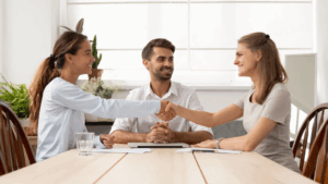 Deux collègues se serrent la main devant un manager, symbolisant la résolution d’un malentendu au travail et le retour à une communication apaisée en équipe.
